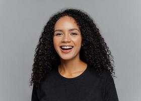 close-up-shot-of-happy-dark-skinned-afro-american-woman-laughs-positively-being-in-good-mood-dressed-in-black-casual-clothes-isolated-on-grey-background-human-emotions-and-feeligs-concept-photo